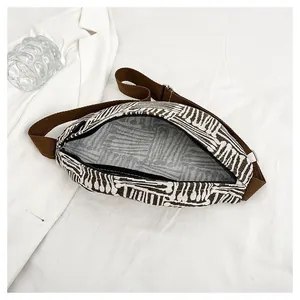 Detail of canvas chest bag featuring black and white geometric stripes and brown strap