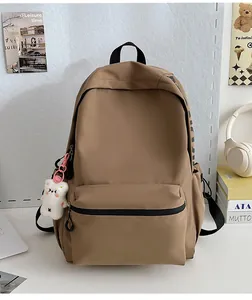 Detailweergave van de kaki nylon rugzak met berenhanger en zijzakken op een bureau geplaatst