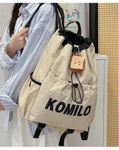 Detail of cream drawstring backpack with black KOMILO print and cute toast charm