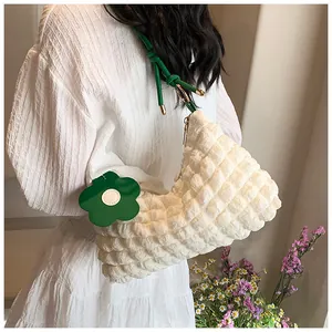 Detail of white popcorn textured tote bag with green leather strap and floral charm
