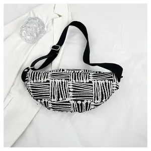 Top view of black and white striped canvas chest bag with adjustable strap on white fabric