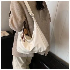 Detail der Hobo-Tasche in Beige glänzend mit verstellbarem Gurt und Seidenschal-Anhänger