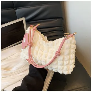 Macro detail of white bubble textured tote bag with pink straps and petal charm