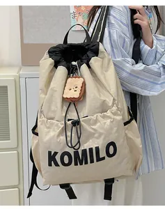 Detail of lightweight beige drawstring backpack featuring black brand logo and toast pendant