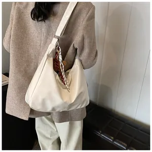 Weiße Hobo-Tasche aus Lackleder mit Bärenanhänger und Seidenschal an der Schulter