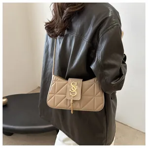 Detail of beige quilted crescent shoulder bag with gold metal fringe S-shaped buckle