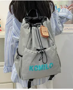 Detail view of grey nylon drawstring backpack with side pockets and toast plush pendant