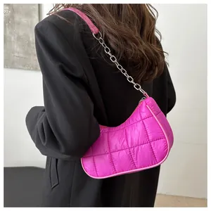 Detalle de bolso bandolera de nailon acolchado rosa brillante con cadena plateada en blazer negro