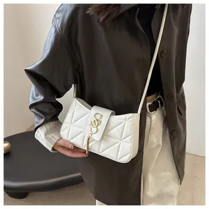 Detail of white quilted crescent bag featuring a gold 'S' buckle and metallic tassel