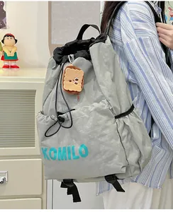 Detail of gray lightweight nylon drawstring backpack with blue logo and plush toast charm