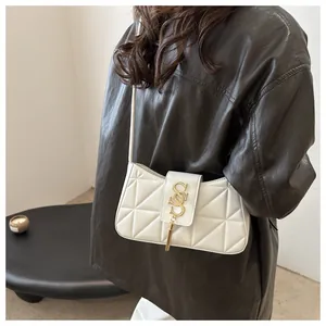 Detail of white quilted crescent bag with golden tassel and metal buckle on shoulder