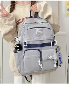 Close-up of dual-tone grey and blue nylon backpack with multiple pockets and plush charm