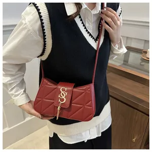 Detail of red quilted crossbody bag with gold tassel hardware on model in a modern room