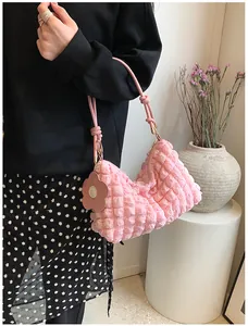 Detailed close-up of pink bubble textured cylinder bag with floral charm accessory