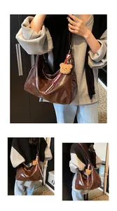 Detailansicht der großen braunen glänzenden Tragetasche mit süßem Plüschbär-Anhänger