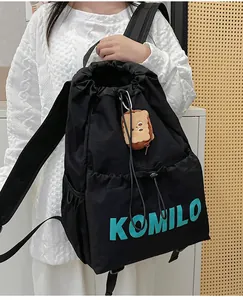 Detail of black drawstring backpack showing water-resistant fabric and plush bread charm