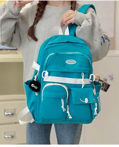Detail of teal college backpack with functional multi-pockets and soft pompom charm