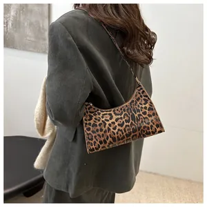 Detailed close-up of leopard print baguette bag texture and glossy synthetic leather finish