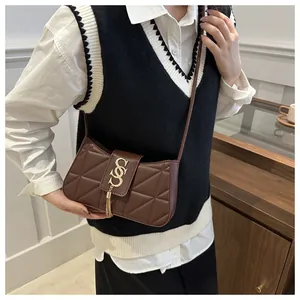 Detail of dark brown leather crossbody bag with gold S-buckle and elegant metal tassels