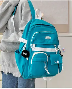 Detail of teal student backpack with multiple pockets and cute plush charm on side