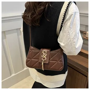 Close-up of quilted crescent shoulder bag with golden double S buckle and tassel detail