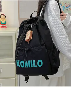 Detail of black drawstring backpack with cyan logo and a toast plush pendant on a model