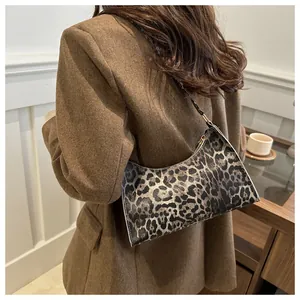 Close-up of stylish leopard print baguette bag on a model in a cafe setting