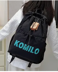 Detail of black drawstring backpack with blue KOMILO print and cute plush toast charm