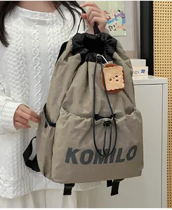 Detail view of khaki drawstring backpack with plush pendant and side mesh pocket