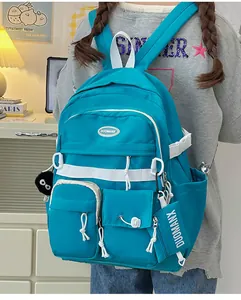 Detail view of bright blue nylon backpack with multiple pockets and plush pendant