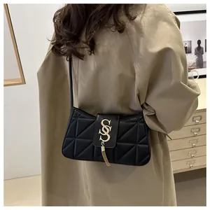 Detail of black quilted shoulder bag featuring gold S-logo and fringe tassel pendant