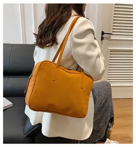 Close-up of ginger yellow frosted leather tote bag showing side zipper and long straps