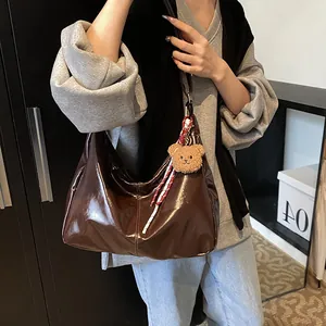 Minimalistische große Hobo-Tasche aus braunem Lackleder mit Bärenanhänger und Bandverzierung