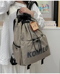 Detail of khaki nylon drawstring backpack with side pockets and plush charm accessory