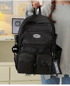 Detail view of the black multi-pocket student backpack with a plush monster pendant