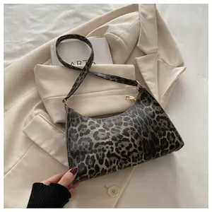 Close-up of leopard print baguette bag with golden zipper on a beige blazer background
