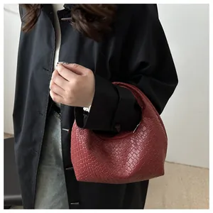 Close-up of wine red woven leather clutch with crescent shape and smooth zipper detail