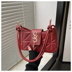 Close-up of burgundy quilted leather bag with gold S-clasp and fringe detail