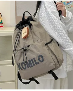 Detail of lightweight drawstring backpack with XOMILO lettering and plush charm pendant