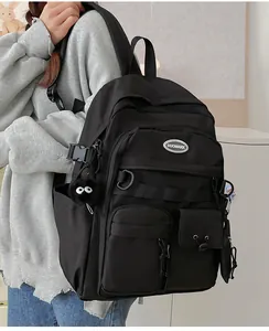 Side view of black nylon backpack featuring functional pockets and a plush monster charm