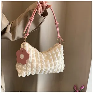 Detail of bubble texture fabric and pink knotted handle on cream cylindrical handbag