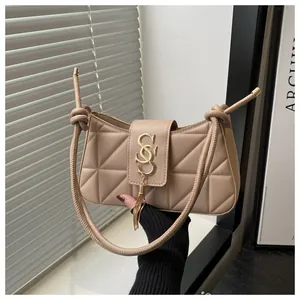 Close-up of beige quilted crescent bag featuring a gold SSS logo buckle with tassel detail