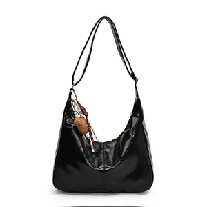 Minimalistische schwarze Hobo-Tasche in Glanzoptik mit Bärenanhänger und Kordel-Detail