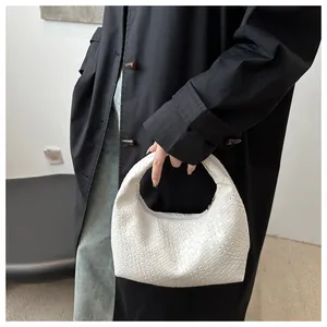 Detail of white woven leather hobo bag showing intricate texture held by model