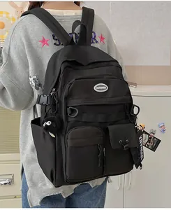 Detail of a black multi-pocket backpack showing the durable material and plush pendant