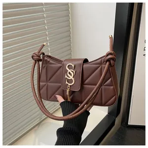 Detail of dark brown quilted shoulder bag featuring gold SOS buckle and tassel charm