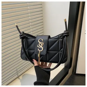 Close-up of black quilted shoulder bag featuring gold tassel and metal logo detail