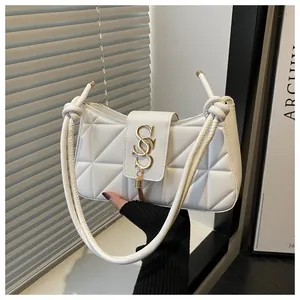 Detail of white quilted crescent bag with gold logo buckle and knotted shoulder strap