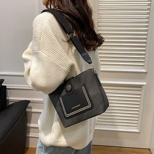 Chic dark grey suede bucket bag with wide fabric strap and gold rivet details for women