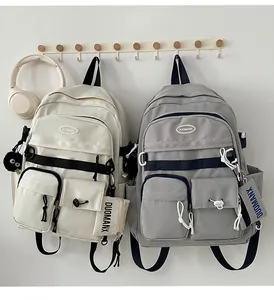 Detail of college-style canvas backpacks in cream and grey with decorative straps